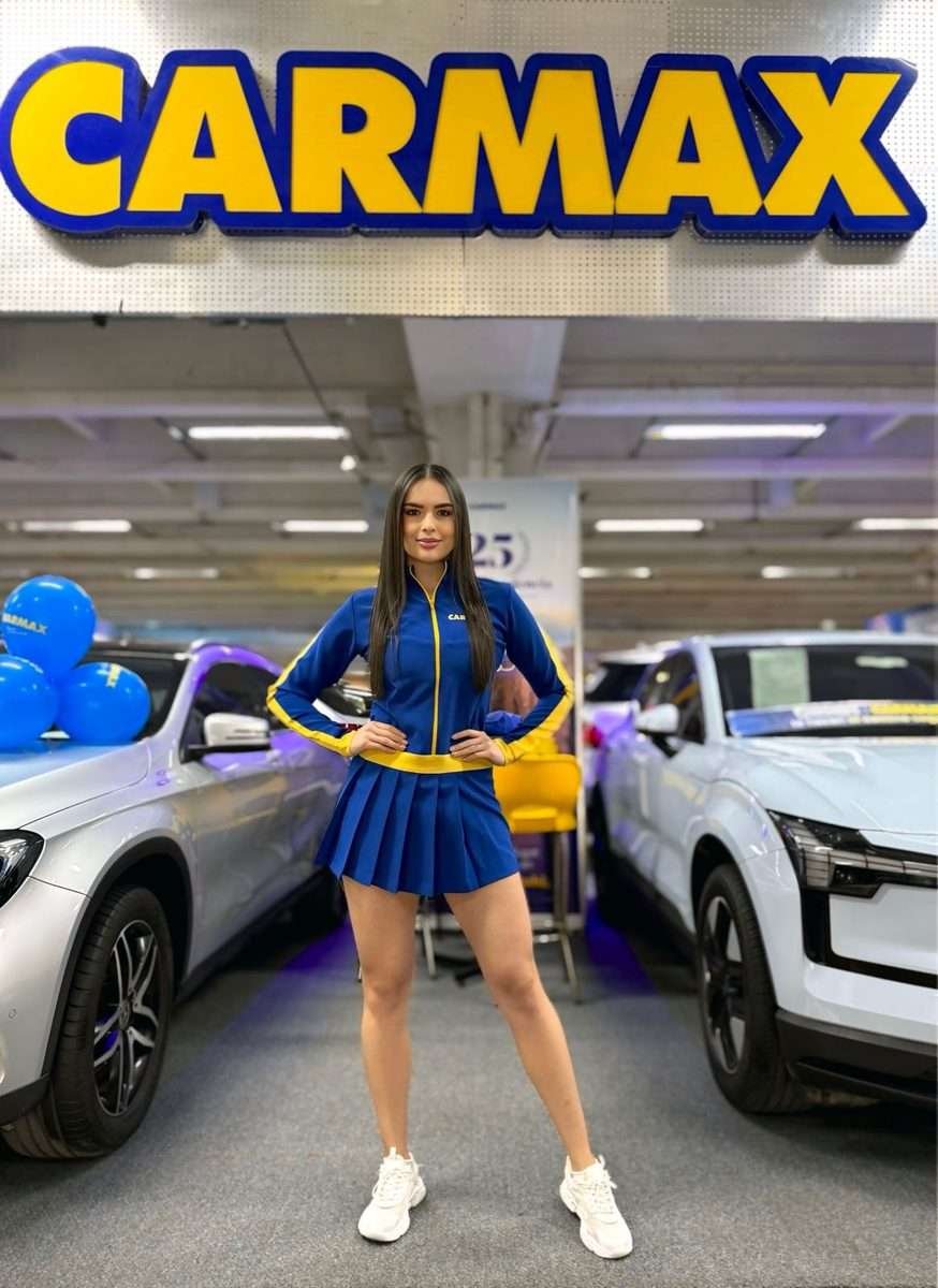 Modelo de AgenciaBTL con uniforme de marca entre vehículos en exhibición